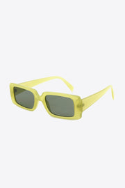 Yellow-green rectangle sunglasses feature softly squared polycarbonate frames, dark-tinted lenses, and wide tapered temples shown in an angled view.