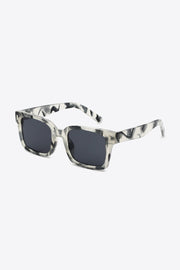 UV400 polycarbonate square sunglasses feature a translucent gray marbled frame, dark lenses, softly rounded corners, and broad temples in a three-quarter view.