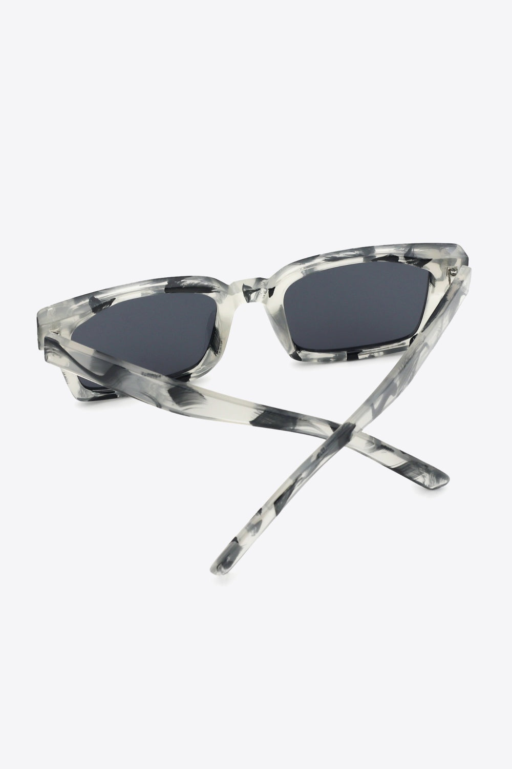 Clear marbled polycarbonate square sunglasses feature broad, softly rounded dark lenses, defined frames, and crossed temples for a bold modern silhouette.