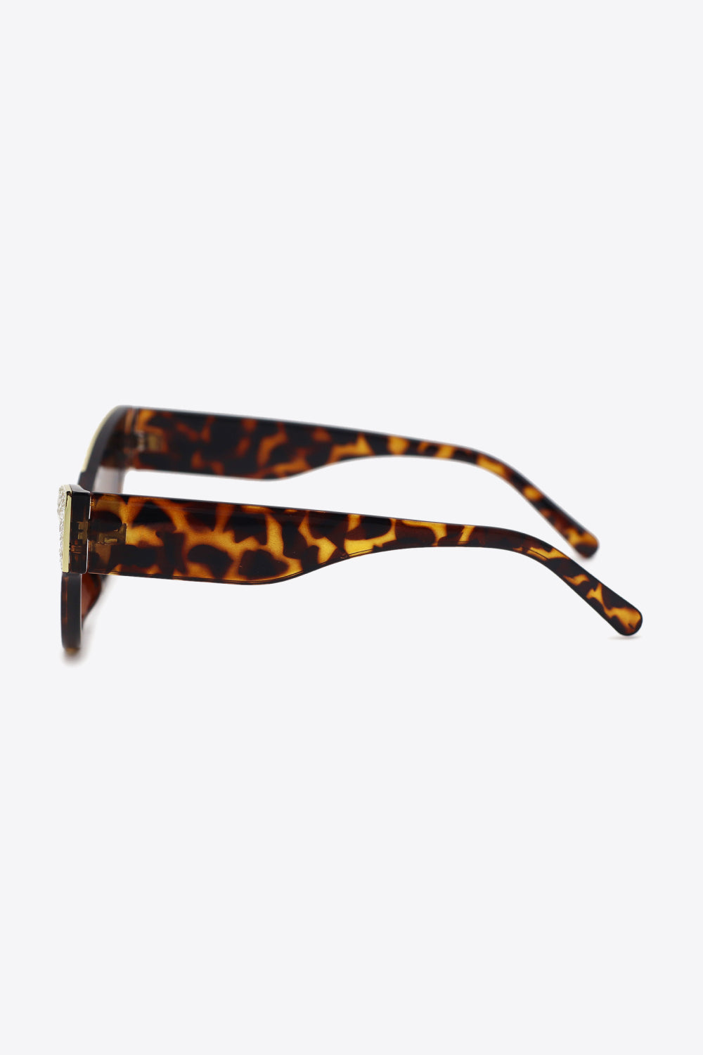 Tortoiseshell cat-eye sunglasses shown in side profile with wide tapered temples, a polished metal-plastic frame, and rhinestone trim along the upper front edge.