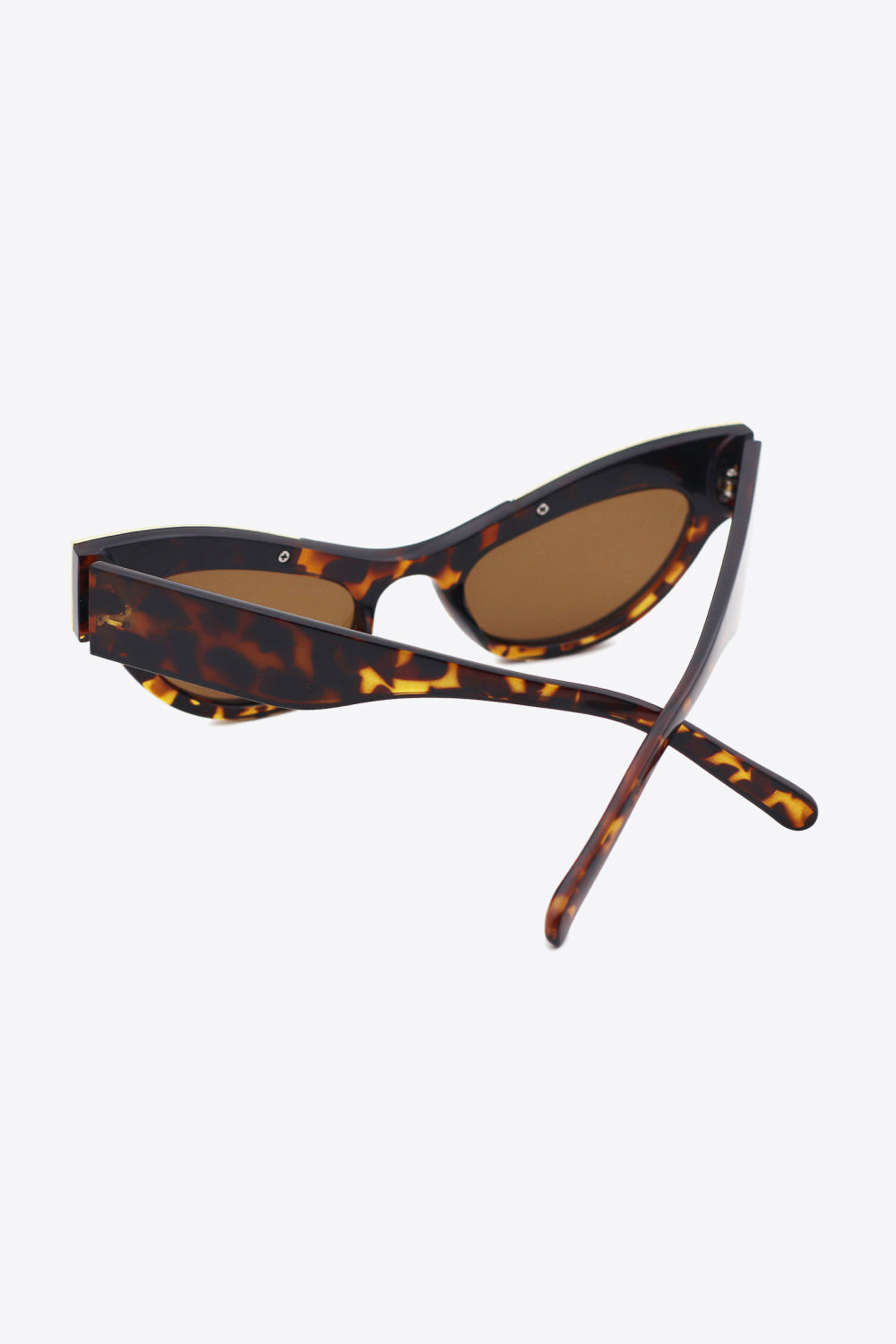Tortoiseshell cat-eye sunglasses feature sharply lifted frames, warm brown lenses, and crossed polycarbonate temples in a polished statement silhouette.