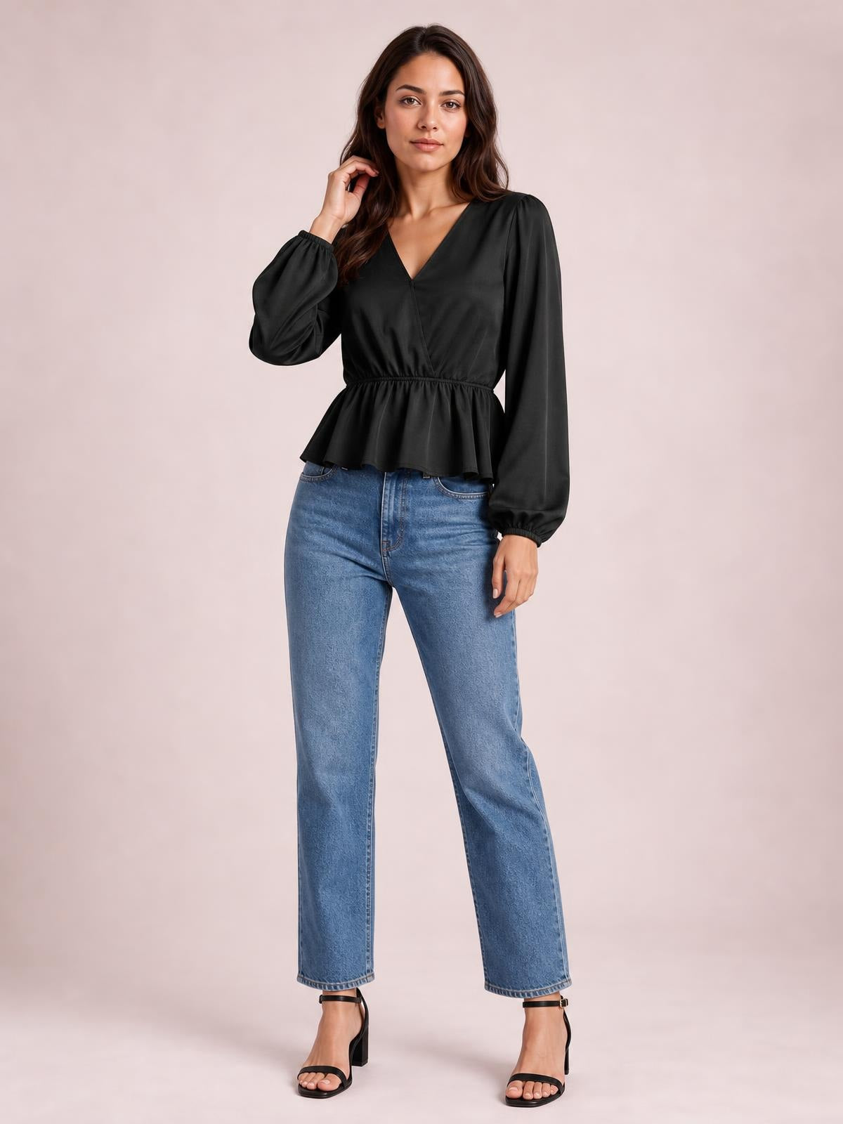 Model wearing a black V-neck peplum blouse with voluminous balloon sleeves, gathered cuffs, an elastic waist, and a flared hem.