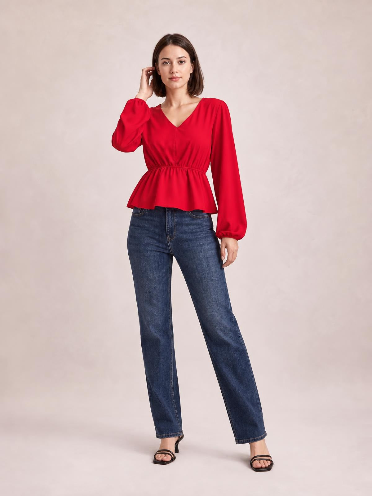 Model poses in a red V-neck peplum blouse with voluminous balloon sleeves, gathered cuffs, a defined waist, and flared hem.