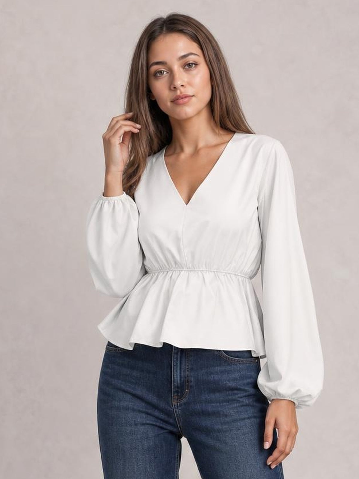 Model poses in a white V-neck peplum blouse with gathered waist, flared hem, and voluminous balloon sleeves with elastic cuffs.
