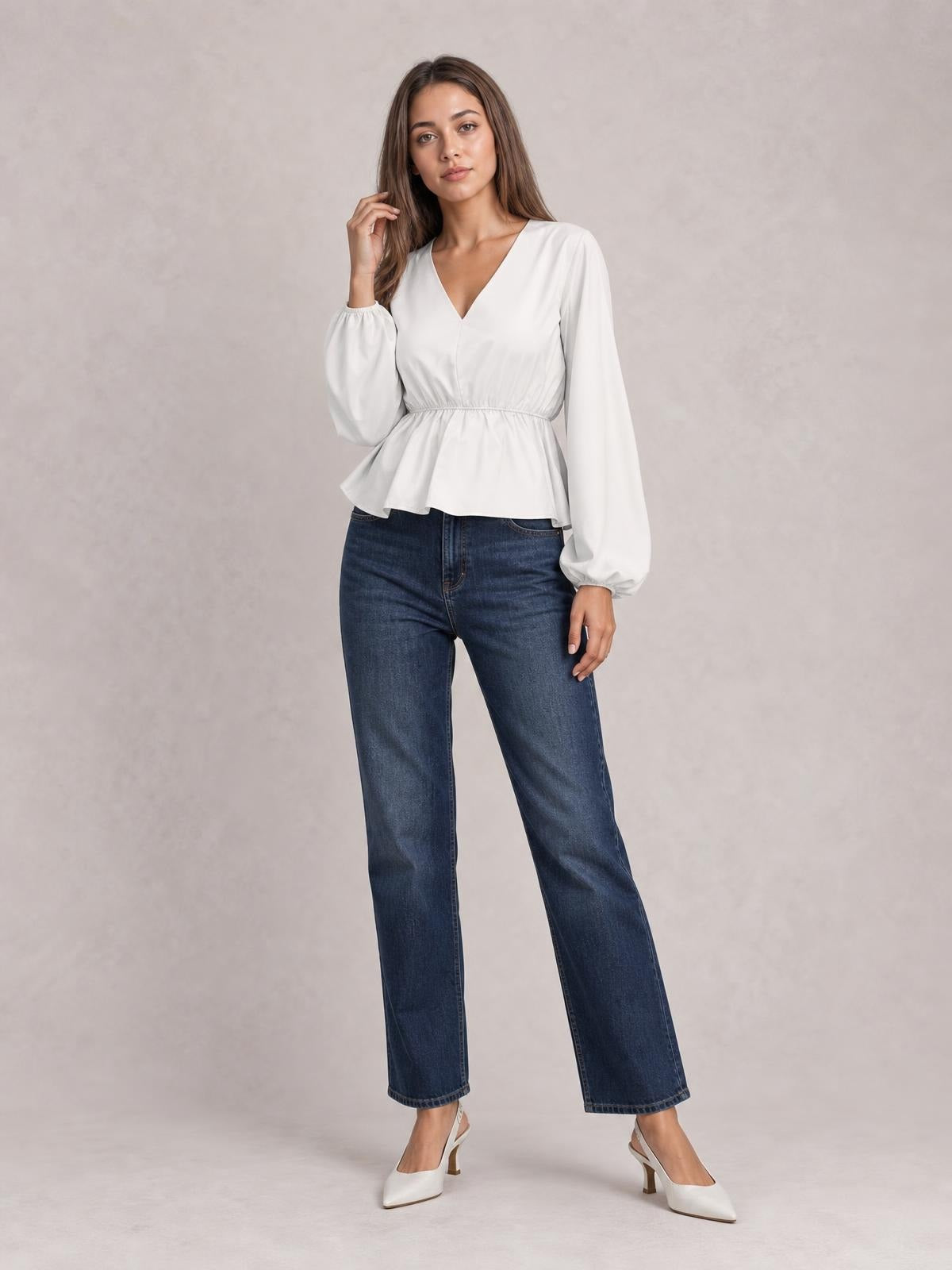 Model poses in a white V-neck peplum blouse with an elastic waist and voluminous balloon sleeves, paired with straight-leg jeans.