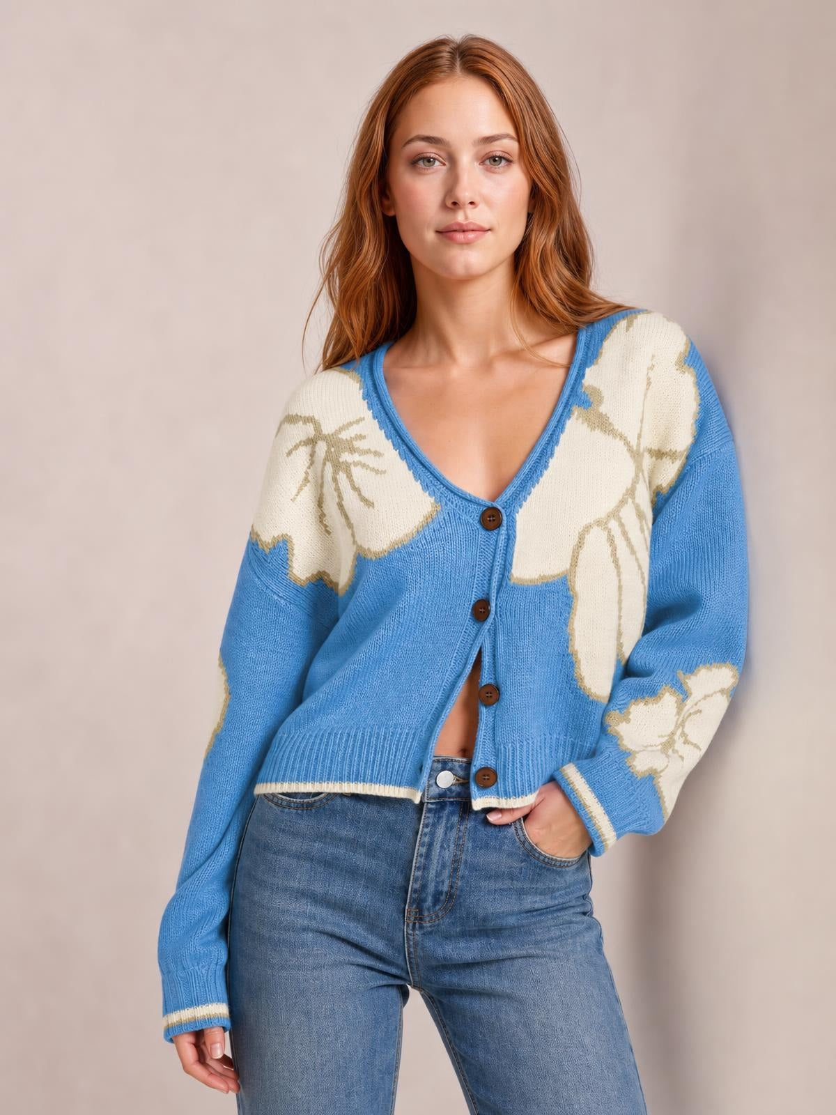 Model wears a blue and cream knit cardigan with a V-neck, button-down front, floral color-block pattern, relaxed silhouette, and ribbed seam details.