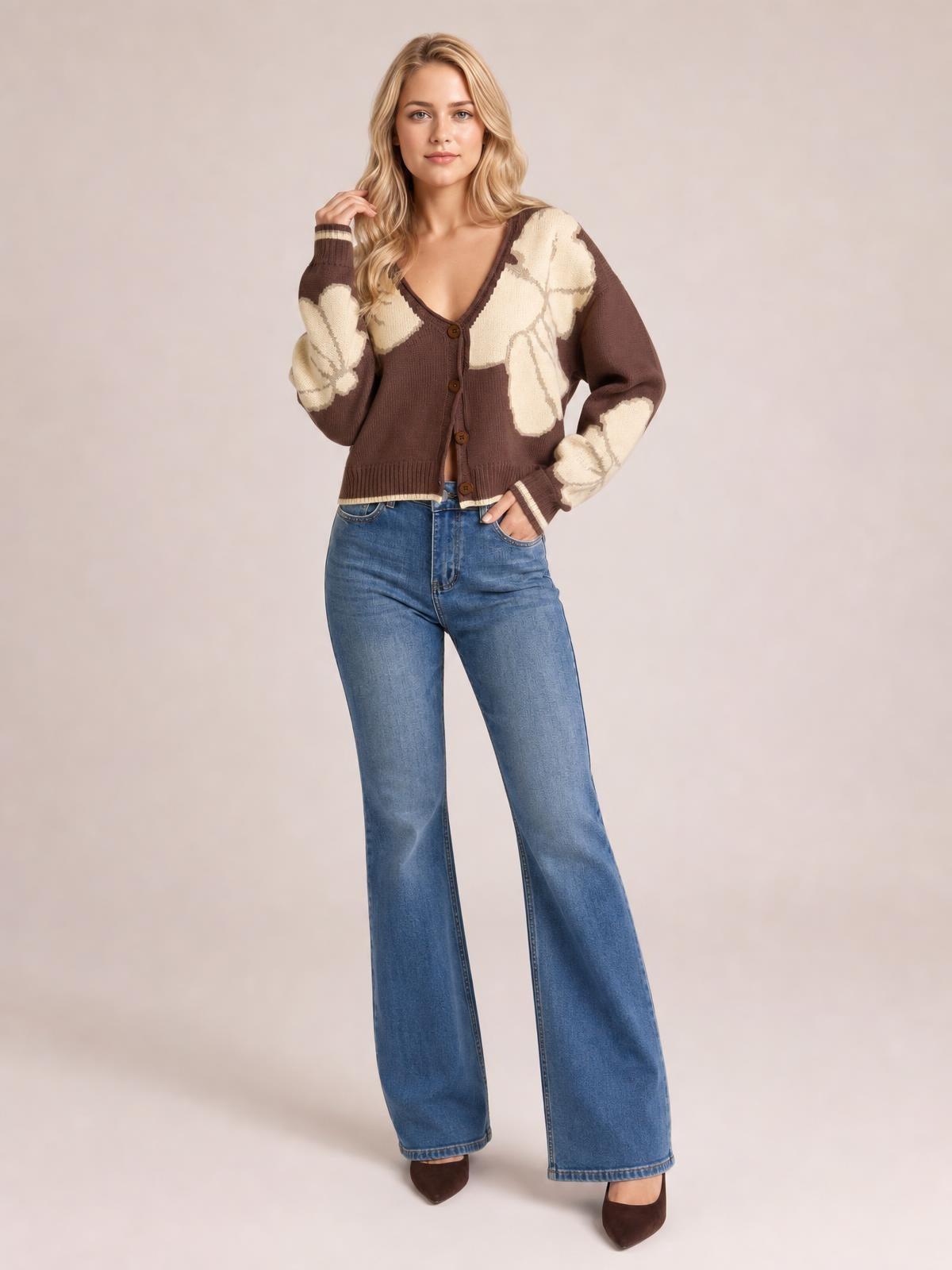 Model poses in a brown and cream V-neck button-down knit cardigan with contrast seam details, long sleeves, and a cropped silhouette.