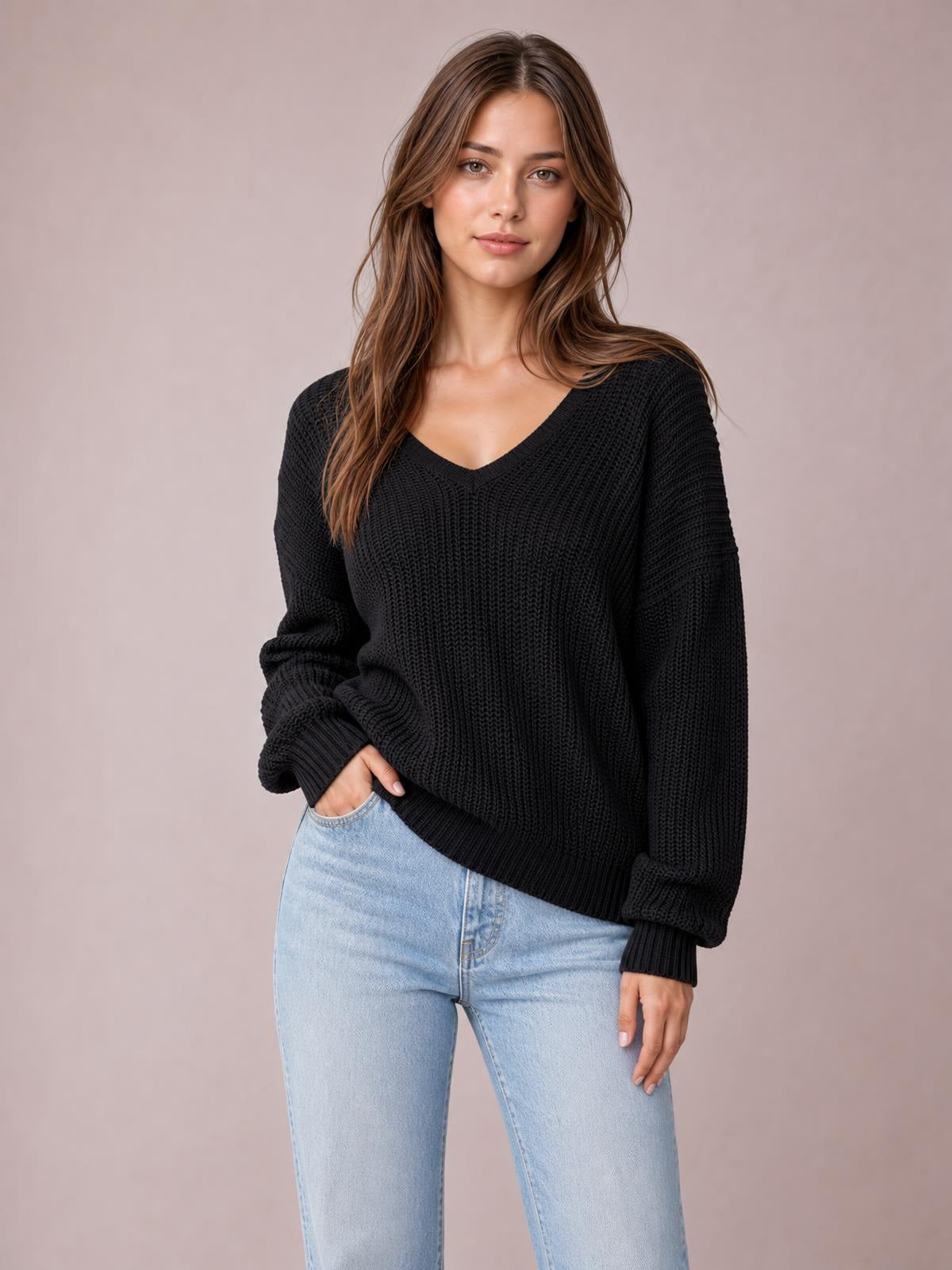 Model poses in a black V-neck drop shoulder sweater with a relaxed oversized silhouette, ribbed cuffs and hem, and textured knit construction.