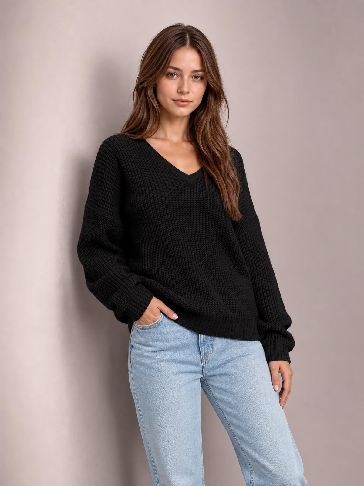 Model wearing a black V-neck drop shoulder sweater with a relaxed oversized silhouette, ribbed cuffs and hem, and textured knit construction.