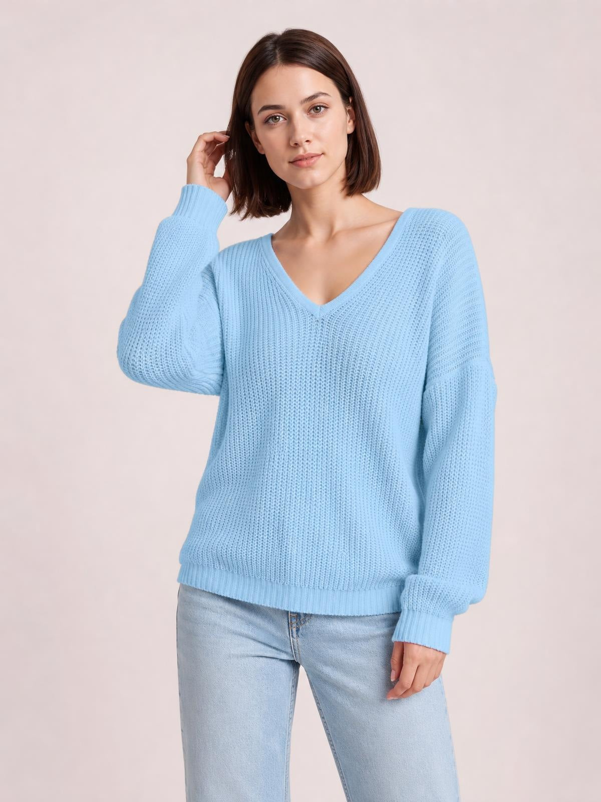 Model poses in a light blue V-neck drop shoulder sweater with a relaxed knit silhouette, ribbed cuffs and hem, and long sleeves.