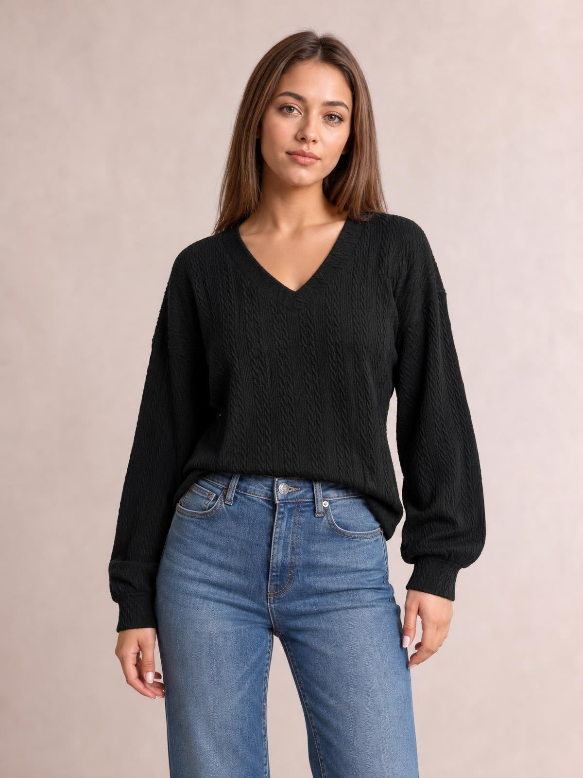 A model stands wearing a black solid V-neck dropped-shoulder blouse with long sleeves and a relaxed, slightly long silhouette.