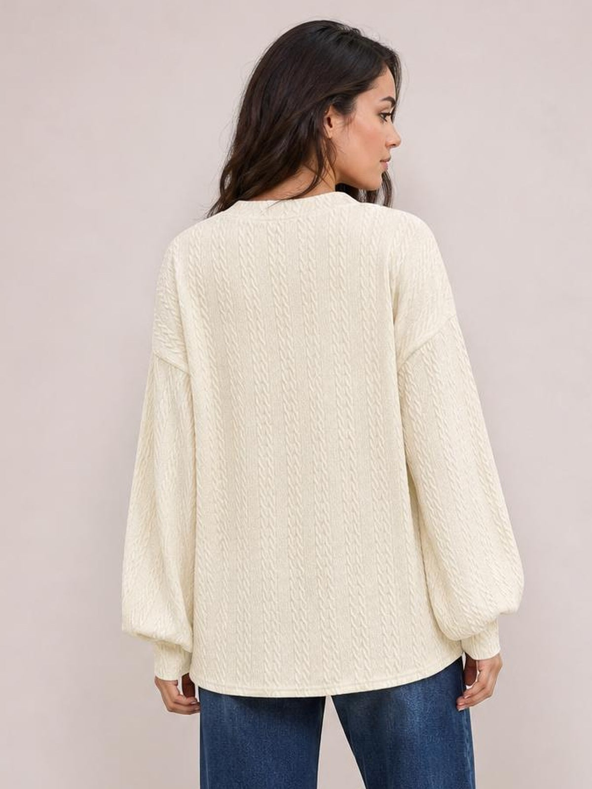 Model stands facing away in a solid ivory blouse with dropped shoulders, long sleeves, relaxed loose fit, and a longer straight silhouette.