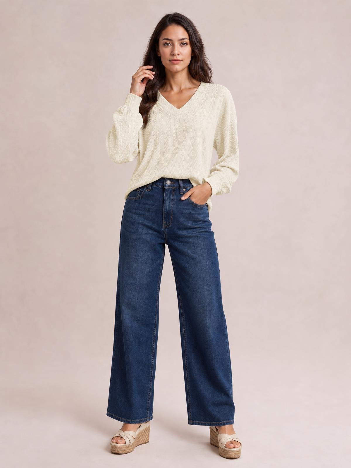 Model wears an opaque ivory V-neck dropped shoulder blouse with a long, relaxed silhouette, textured construction, and long regular sleeves.
