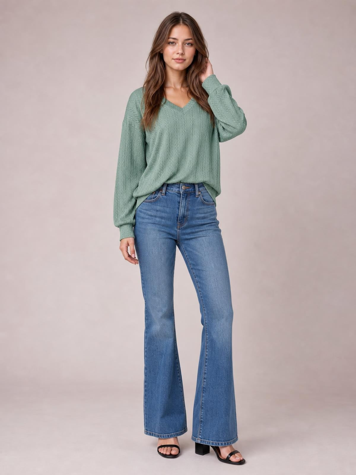 Model poses in a sage green solid V-neck dropped shoulder blouse with long sleeves, a relaxed long silhouette, and textured construction.