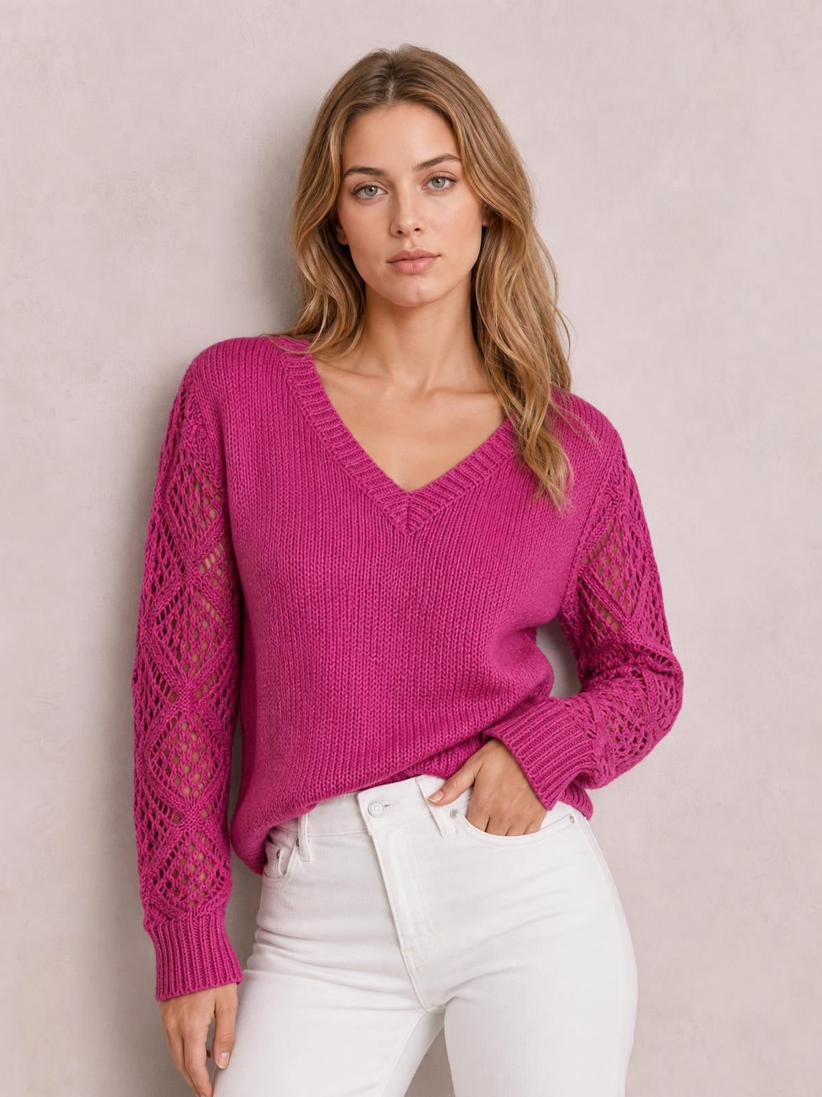 Model wears a magenta V-neck knit sweater with openwork hollow-out sleeves, ribbed cuffs and hem, and a relaxed silhouette while standing with one hand in her pocket.