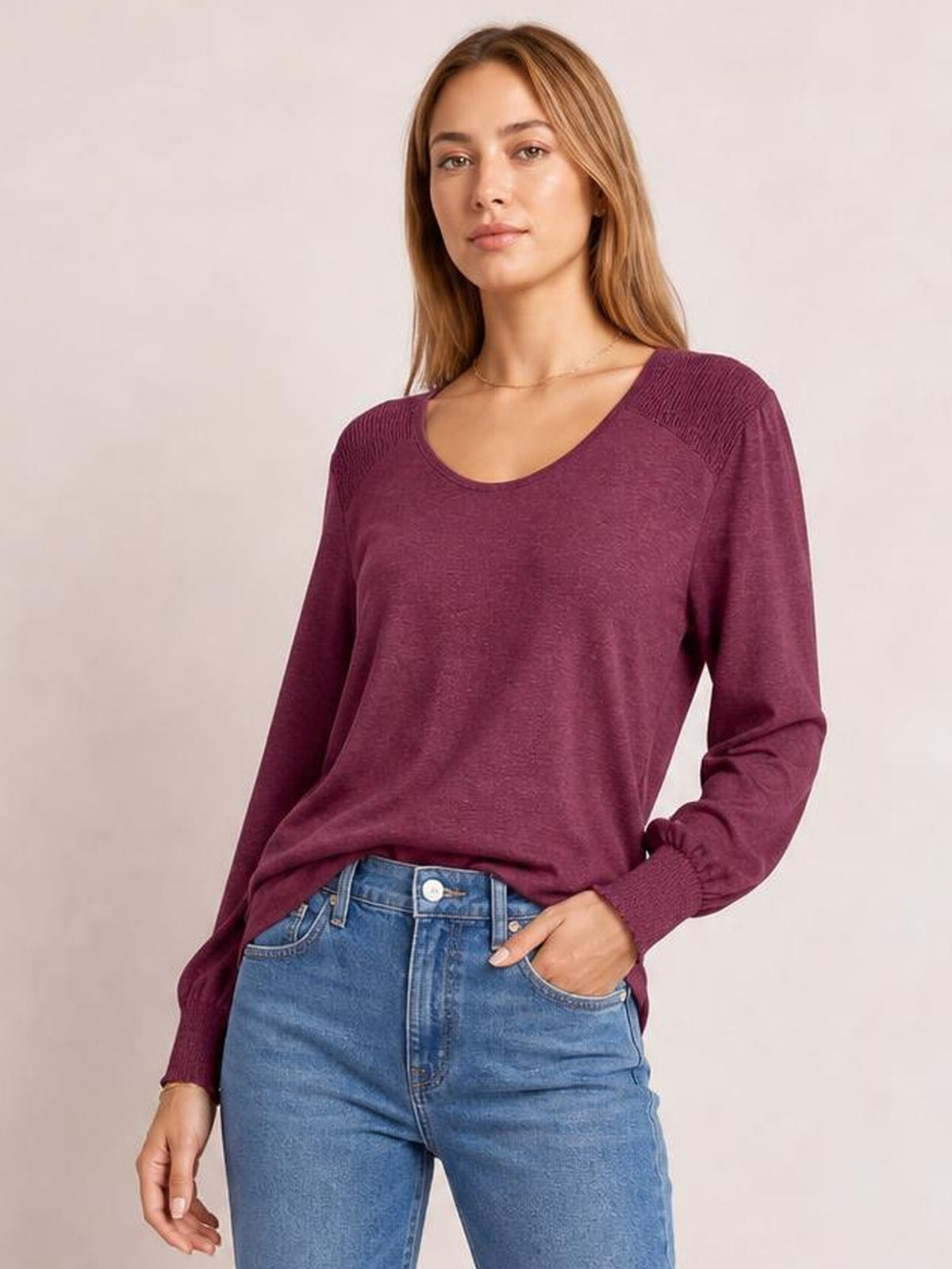 A model wears a burgundy V-neck T-shirt with a relaxed silhouette, gathered lantern sleeves, elastic cuffs, and a soft, draped construction.