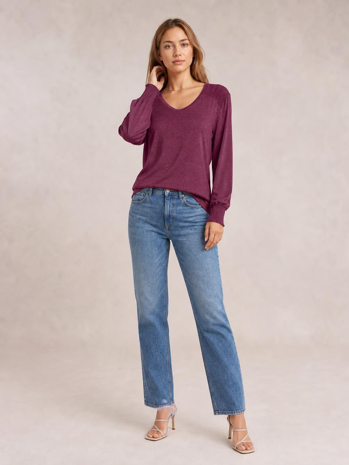 Model poses in a burgundy V-neck lantern sleeve T-shirt with gathered cuffs and a relaxed straight silhouette, paired with jeans.
