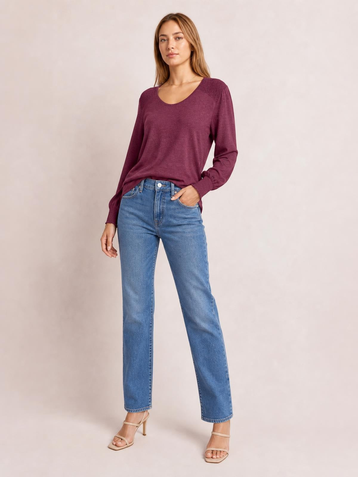 Model wears a plum lantern-sleeve T-shirt with a wide scoop neckline, gathered shoulder panels, fitted cuffs, and a relaxed silhouette with one hand in her jeans pocket.