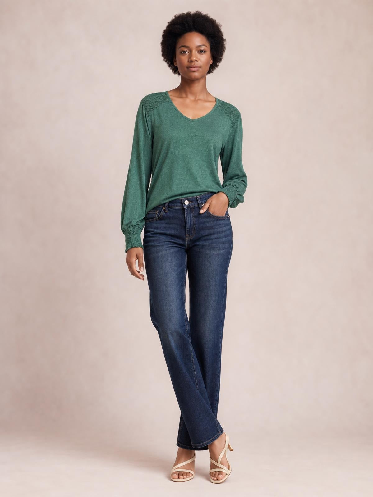 A model wears a green V-neck T-shirt with long lantern sleeves, gathered cuffs, and a relaxed silhouette while standing with one hand in her jeans pocket.