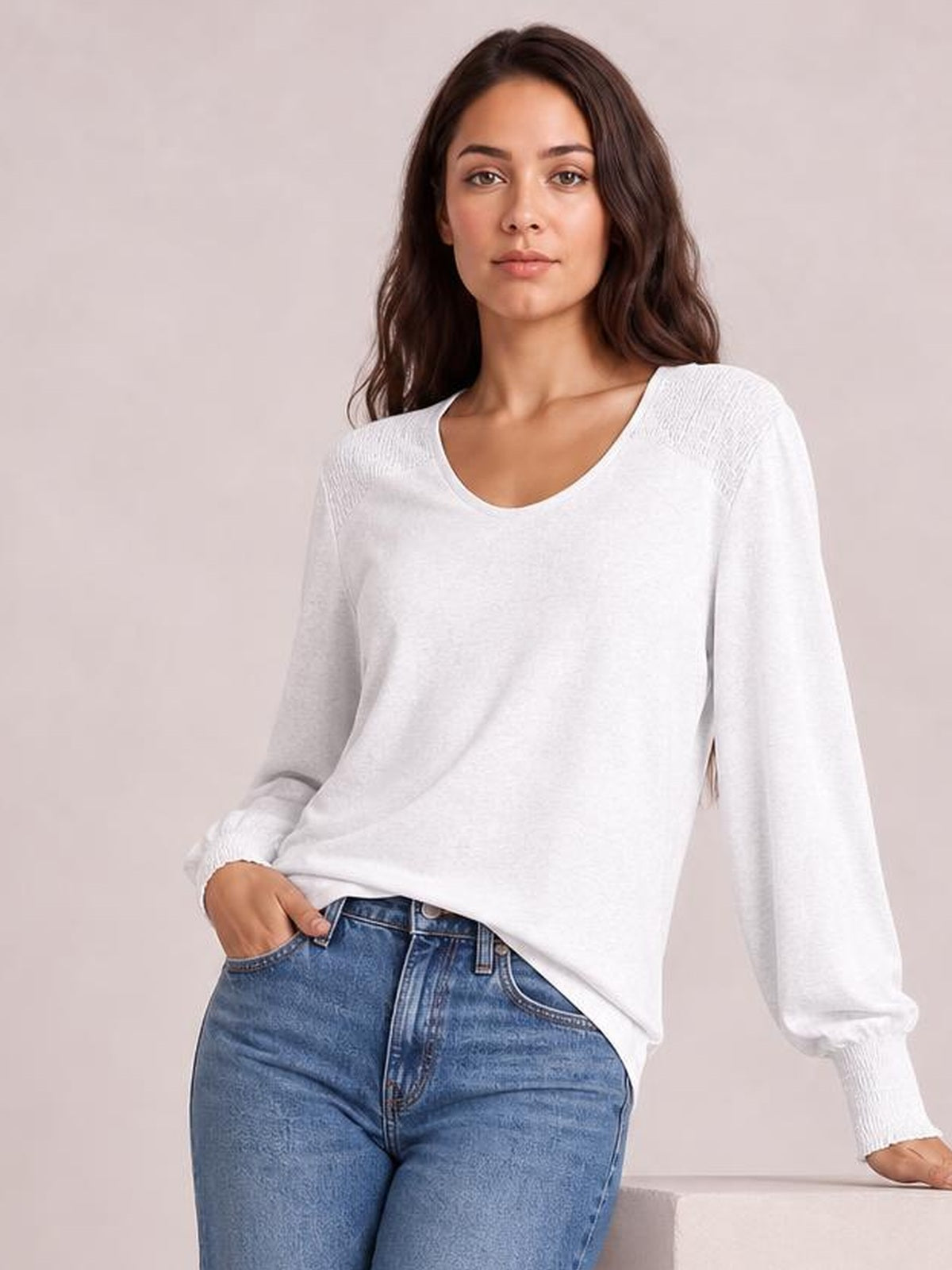 A model poses in a white long-sleeve T-shirt with a relaxed silhouette, softly gathered lantern sleeves, ribbed cuffs, and a wide neckline.