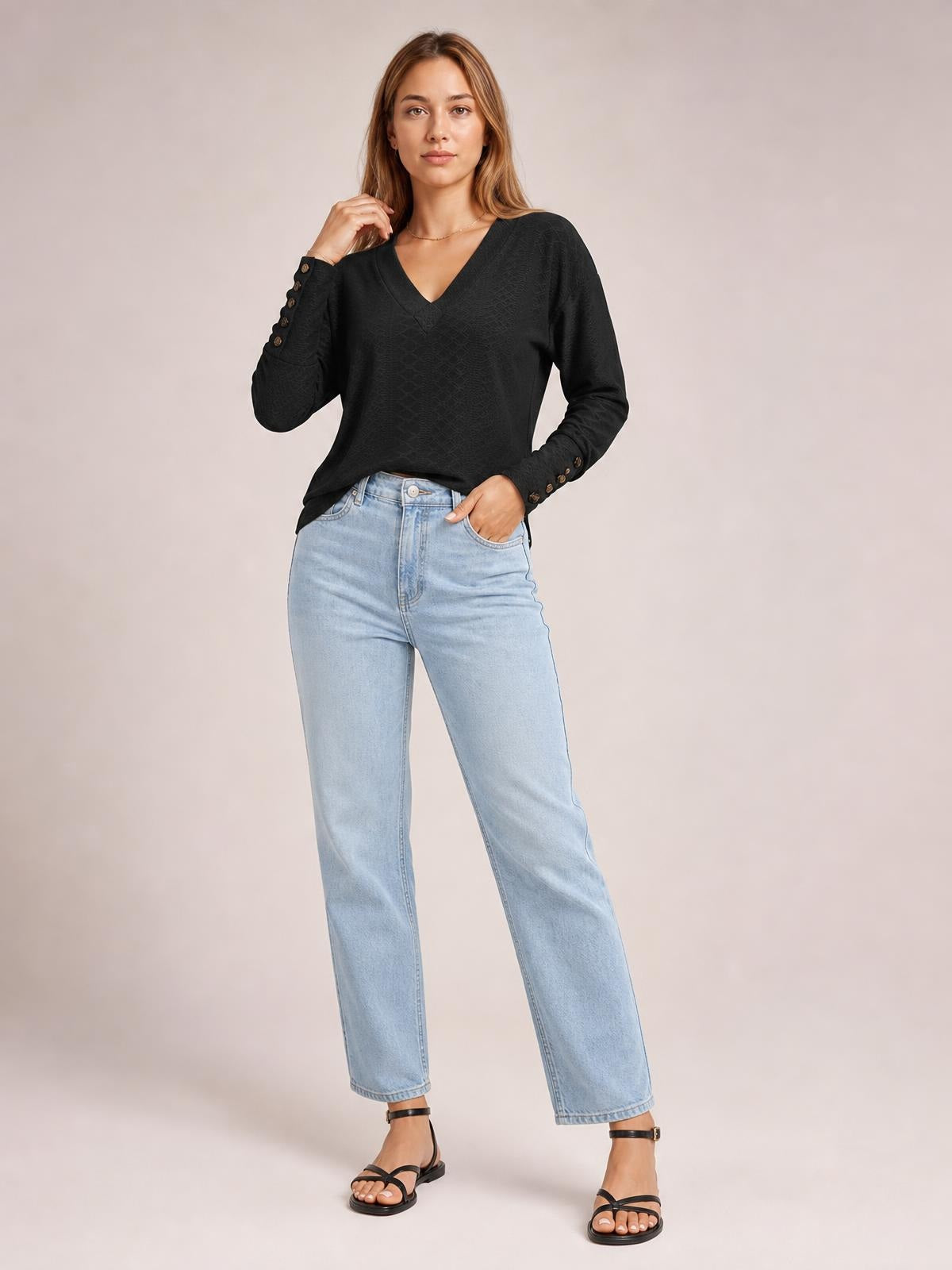 Model wearing a black V-neck long sleeve blouse with a regular relaxed silhouette, subtle textured pattern, and button details at the cuffs.