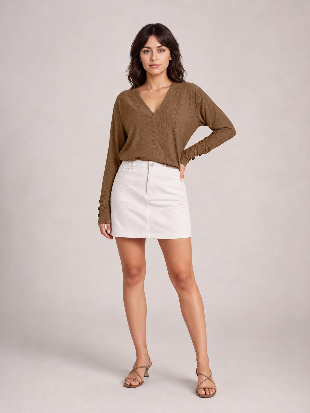 A model poses with one hand on her hip, wearing a brown V-neck long sleeve blouse with a relaxed regular silhouette and buttoned cuffs.