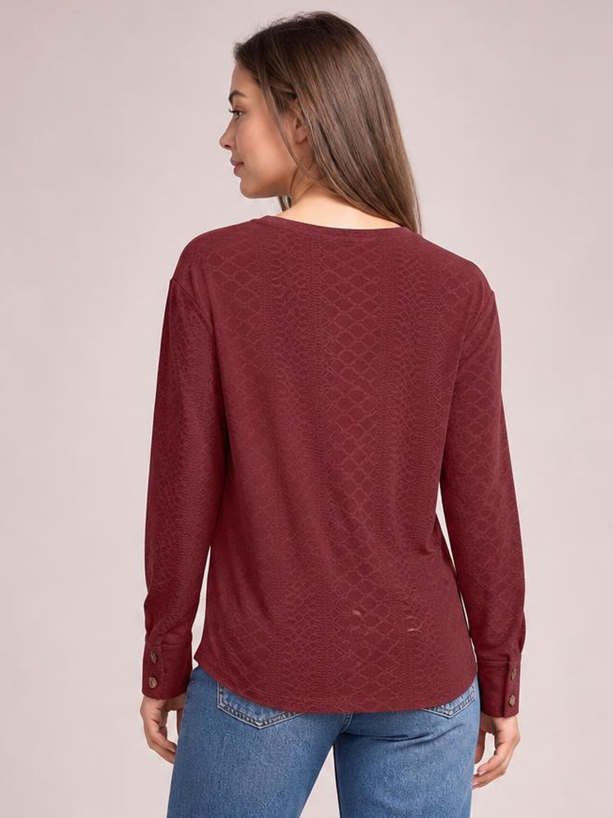 Model looks over her shoulder wearing a burgundy long-sleeve blouse with a relaxed regular silhouette, smooth back, and buttoned cuffs.