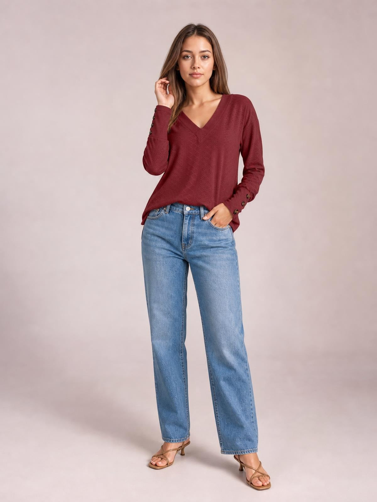 Model wearing a solid burgundy V-neck long sleeve blouse with a relaxed regular silhouette, buttoned cuffs, and a slightly curved hem.