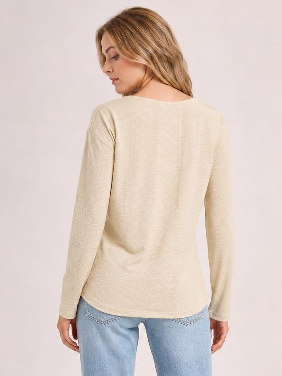 A model looks over her shoulder while wearing a cream solid long-sleeve blouse with a relaxed silhouette, regular length, and rounded hem.