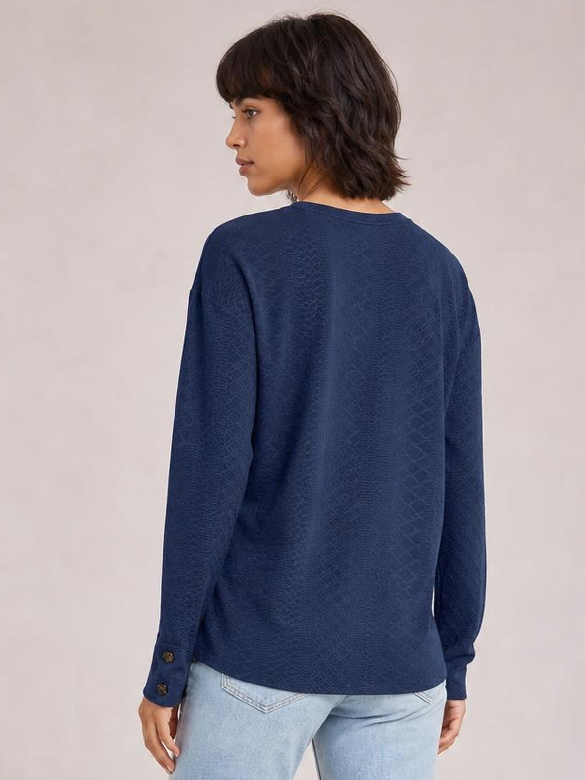 Model looks over her shoulder wearing a dark navy long-sleeve blouse with a relaxed regular silhouette, straight hem, and buttoned cuffs.
