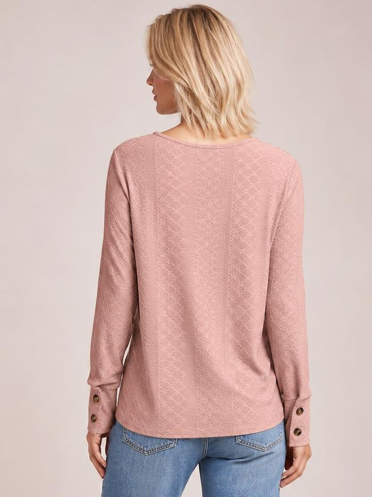 Model shown from behind wearing a dusty pink long-sleeve blouse with a regular silhouette, textured pattern, straight hem, and buttoned cuffs.