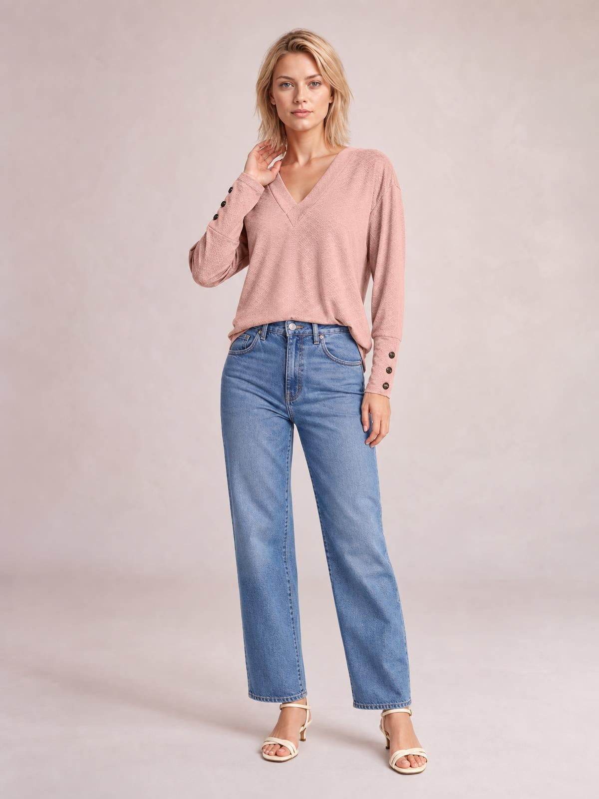 Model poses in a dusty pink V-neck long sleeve blouse with a relaxed regular silhouette, subtle texture, and buttoned cuffs.