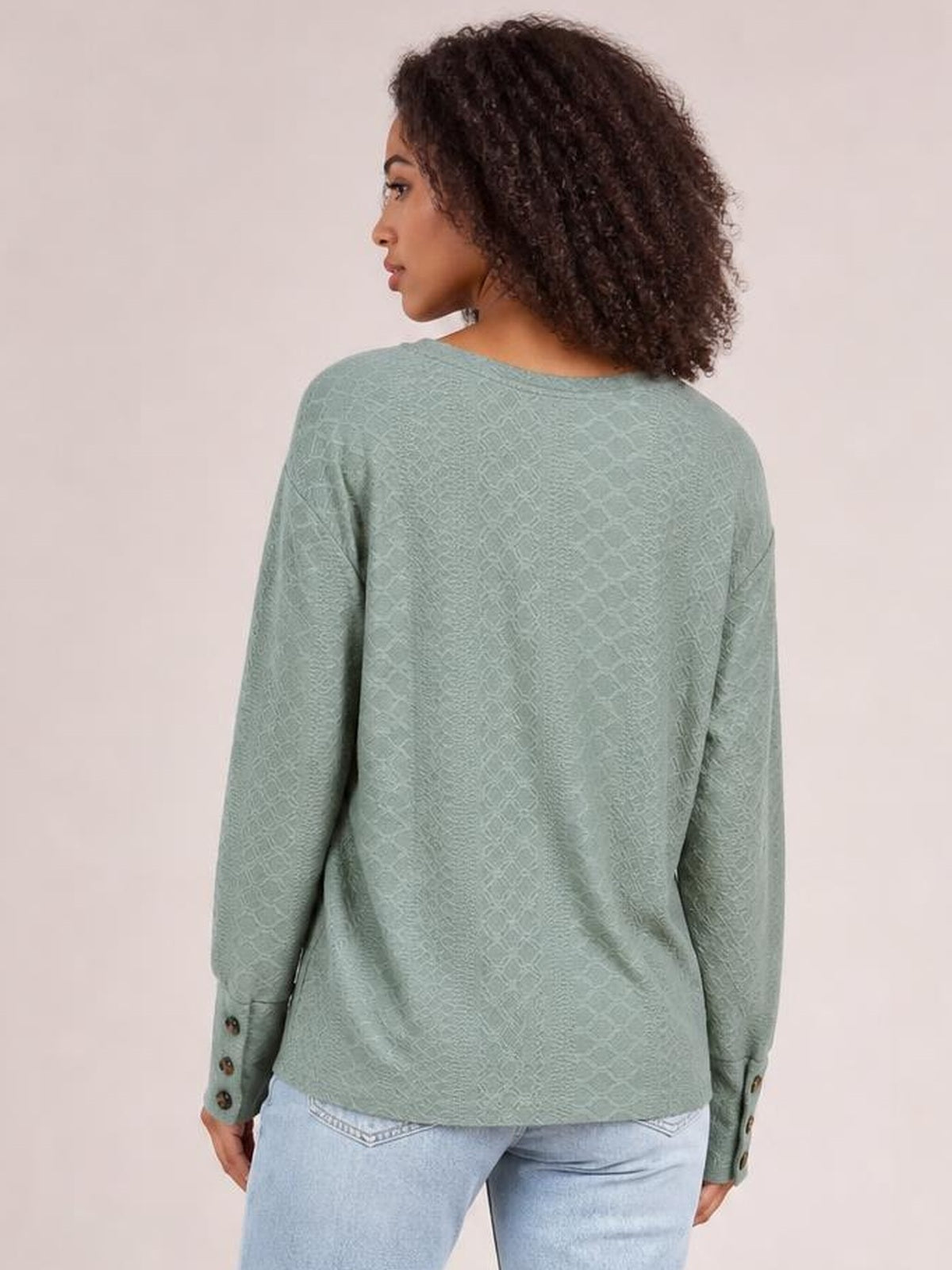 Model shown from the back wears a sage green long-sleeve blouse with a relaxed regular silhouette, textured finish, and buttoned cuffs.