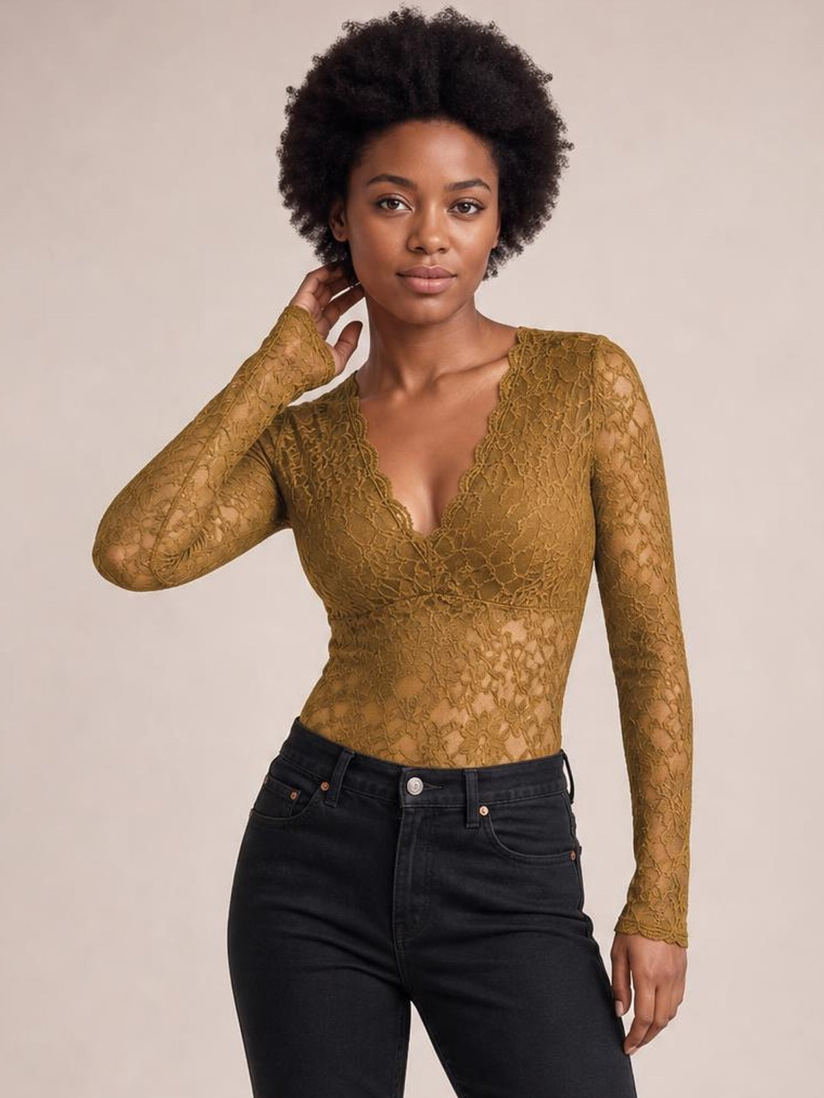 Model wears a mustard-brown V-neck long sleeve lace top with a fitted silhouette, floral lace construction, and slight stretch, touching her neck.