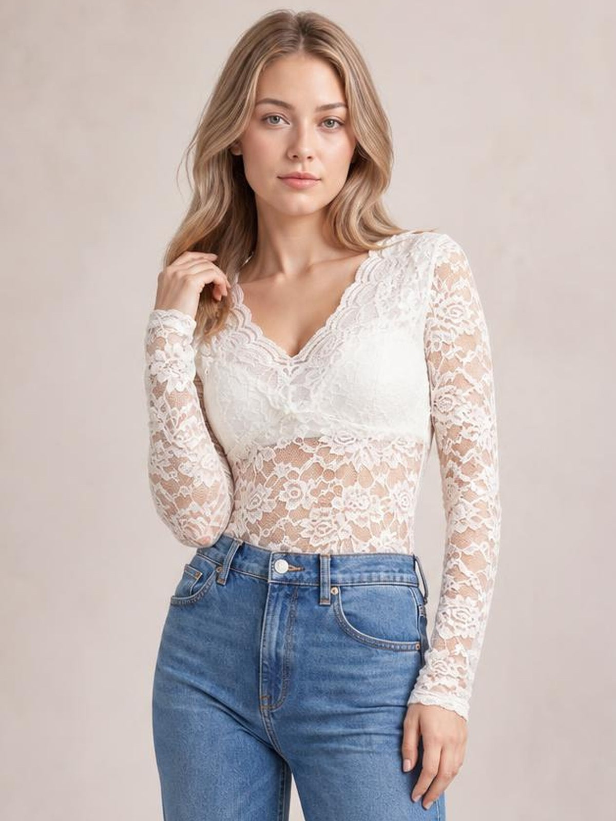 Model wears a white V-neck long sleeve lace top with a fitted silhouette, scalloped neckline, sheer lace sleeves, and floral lace construction.