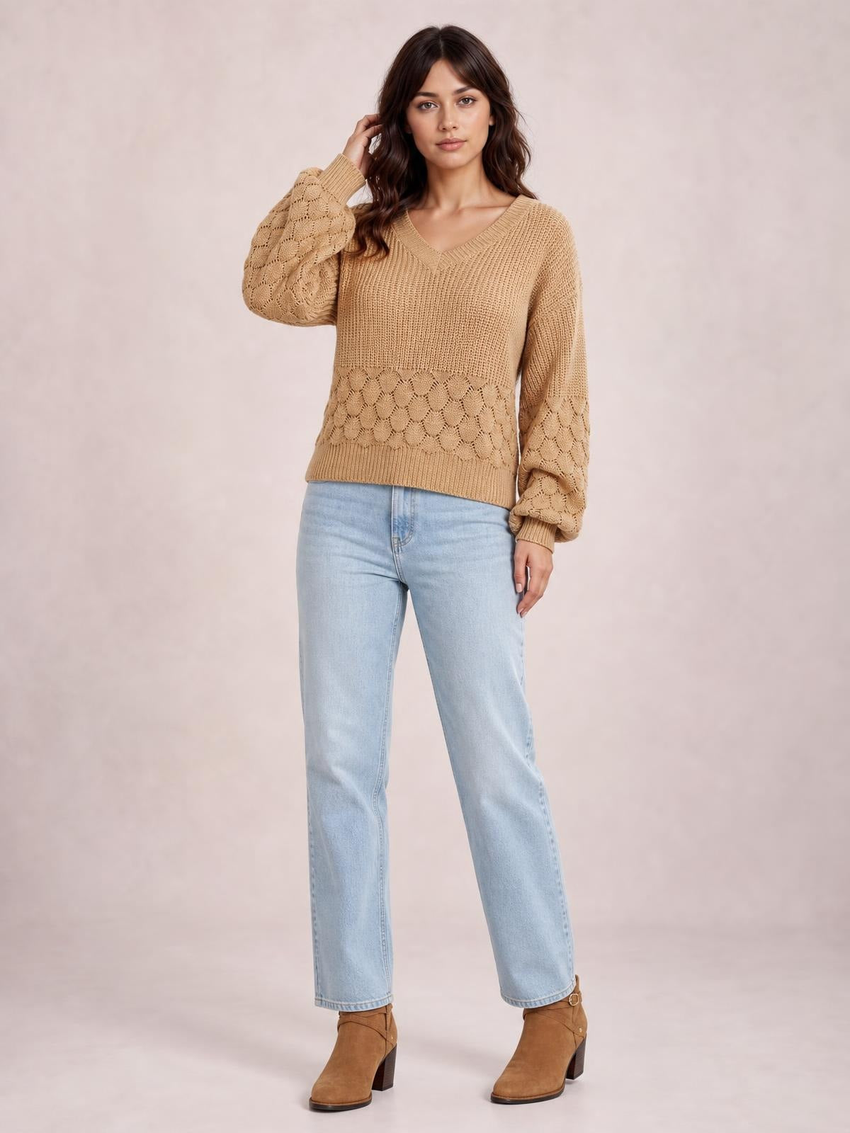 Model poses in a relaxed-fit camel V-neck long sleeve sweater with ribbed trim, open-knit textured panels, and a straight silhouette.
