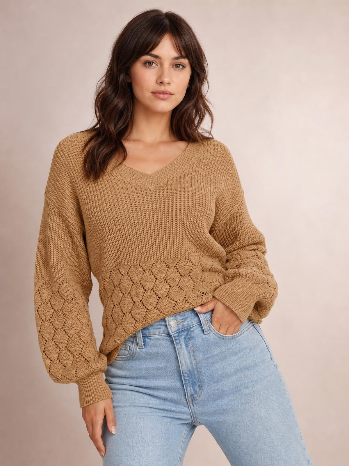 Model wearing a relaxed tan V-neck long sleeve sweater with ribbed cuffs and decorative open-knit leaf detailing on the sleeves and hem.