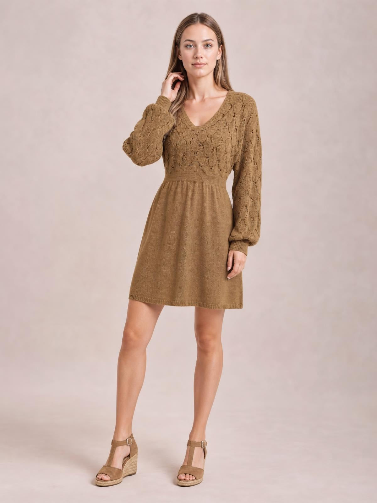 Model poses in a brown V-neck long sleeve sweater dress with openwork knit texture, fitted waist, and softly flared above-knee silhouette.