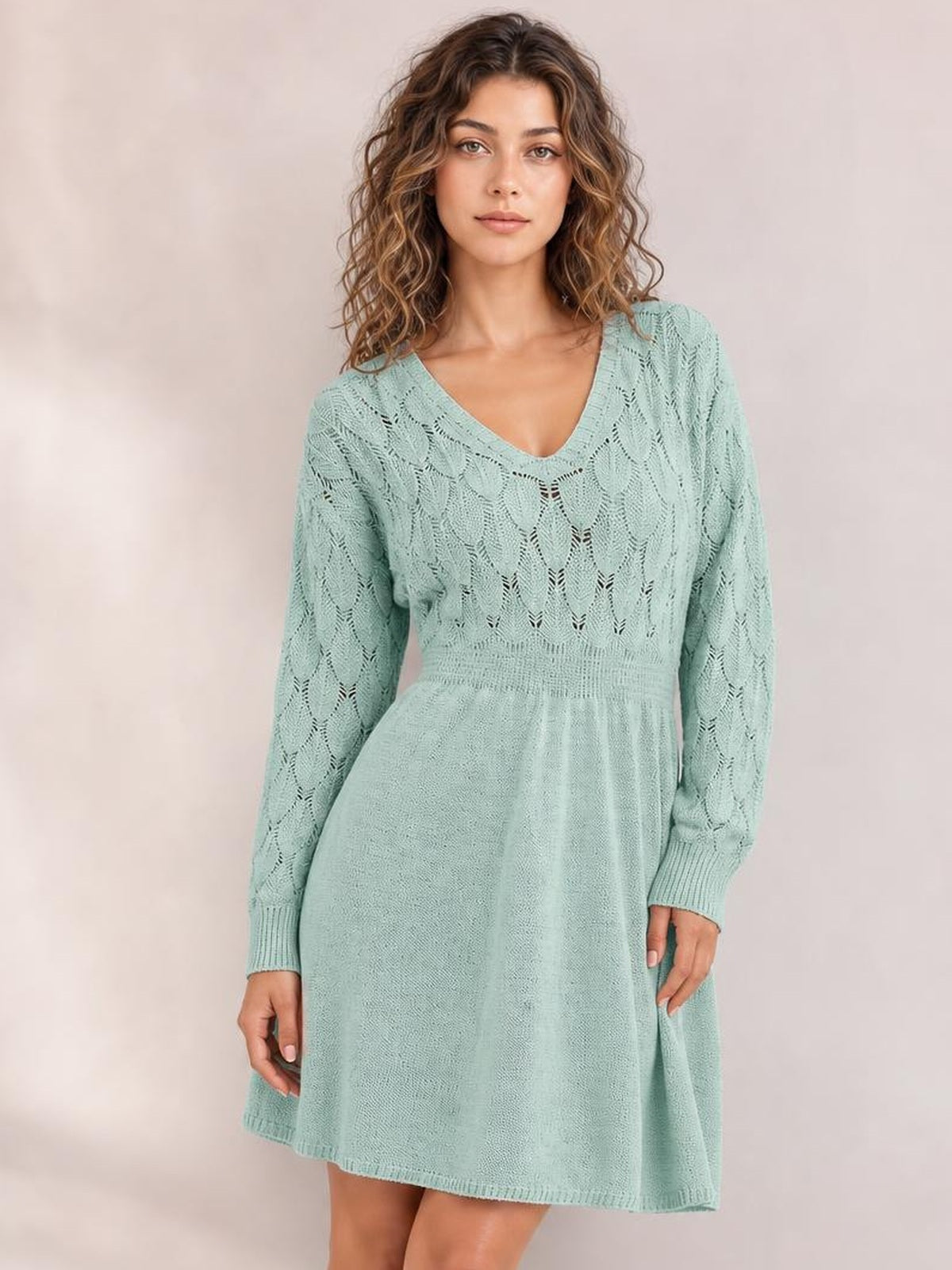Model wears a mint green V-neck long sleeve sweater dress with openwork knit detailing, a defined waist, ribbed cuffs, and a flared short silhouette.