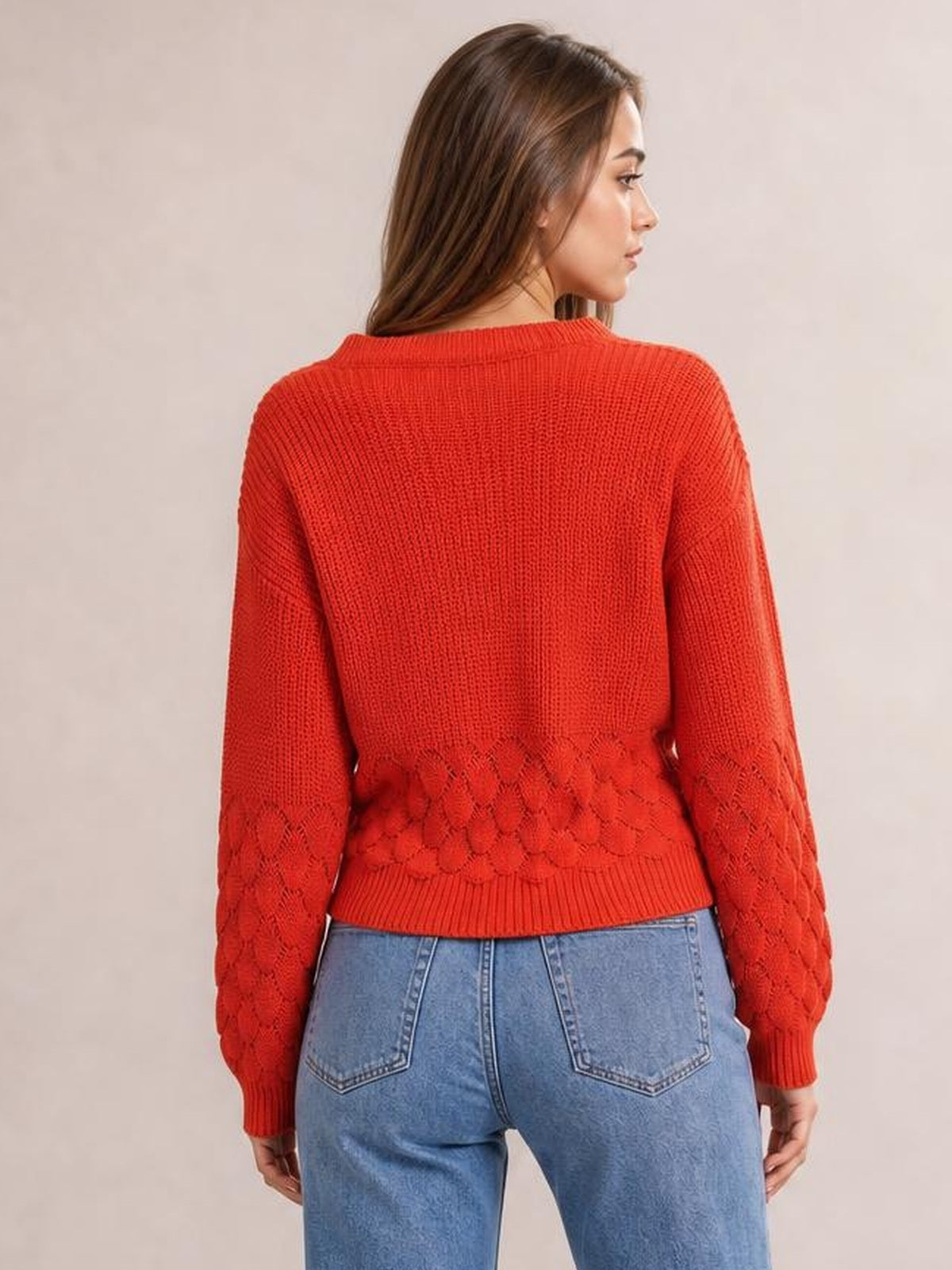 Model shown from behind wears a relaxed-fit red long sleeve sweater with ribbed trims and textured diamond-knit detailing at the lower sleeves and hem.