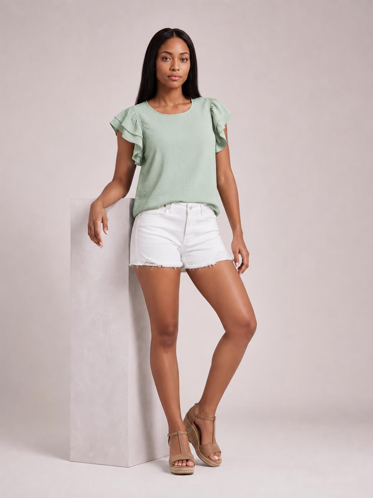 Model poses in a relaxed mint green blouse with layered ruffled cap sleeves, a rounded neckline, and a loose straight silhouette.