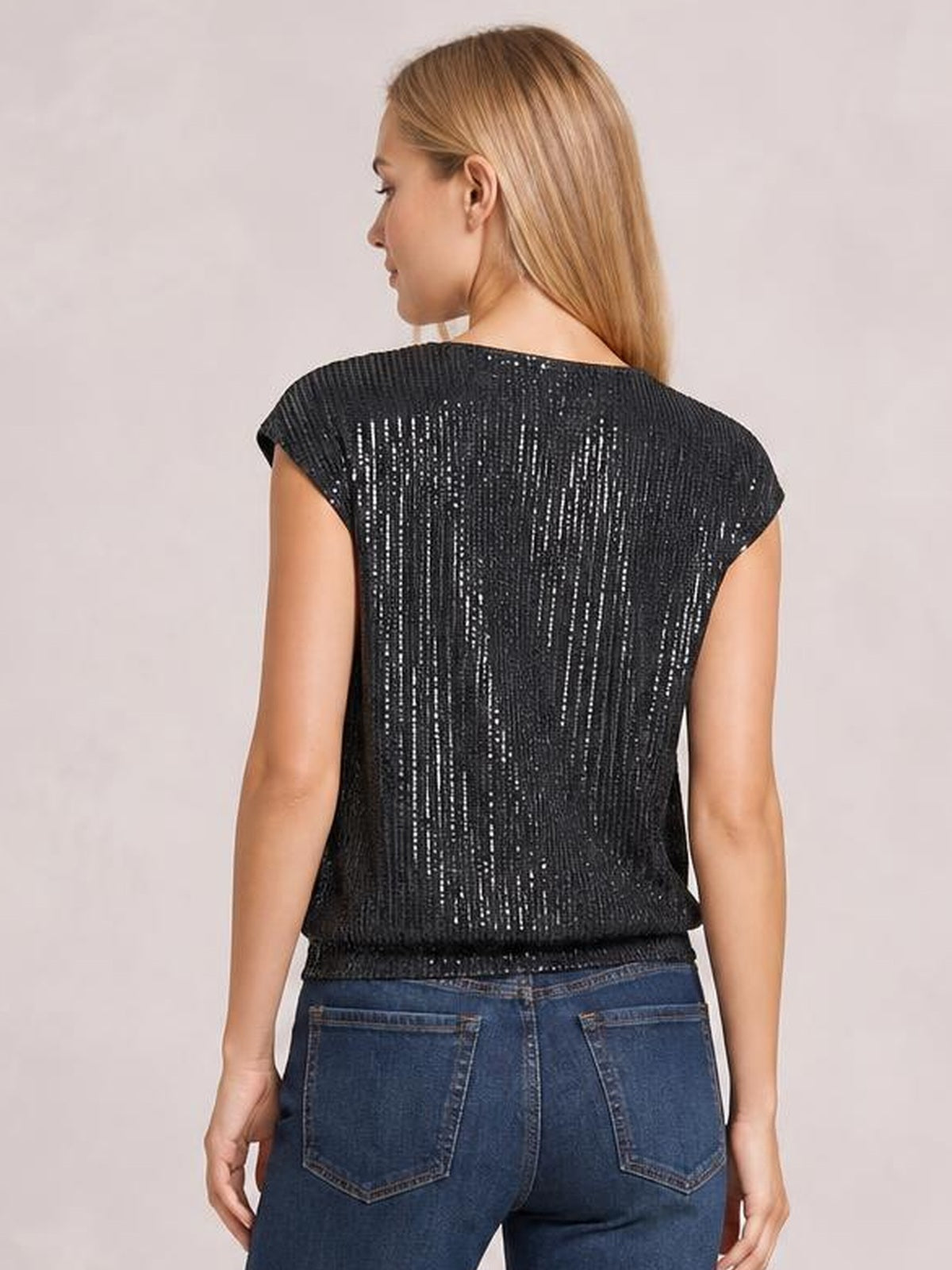 Back view of a model wearing a black sequin cap sleeve top with shimmering vertical embellishment and a relaxed, straight silhouette.