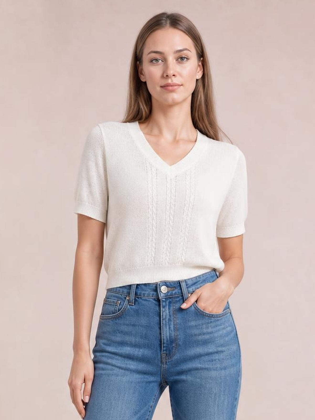 Model wears a white V-neck short sleeve knit top with a relaxed silhouette, textured front knit, ribbed cuffs and hem, and one hand in her jeans pocket.