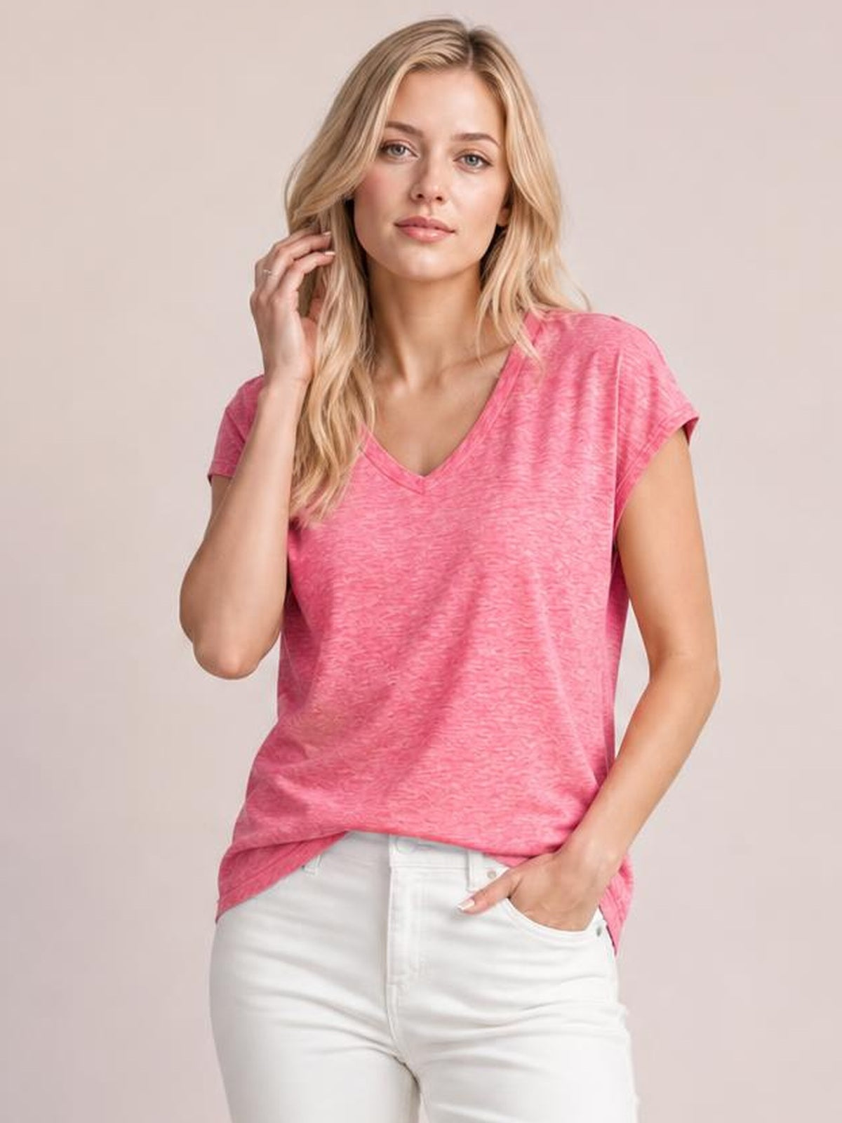 Model wearing a pink V-neck short sleeve T-shirt with a relaxed straight silhouette and curved hem, posing with one hand in her pocket.