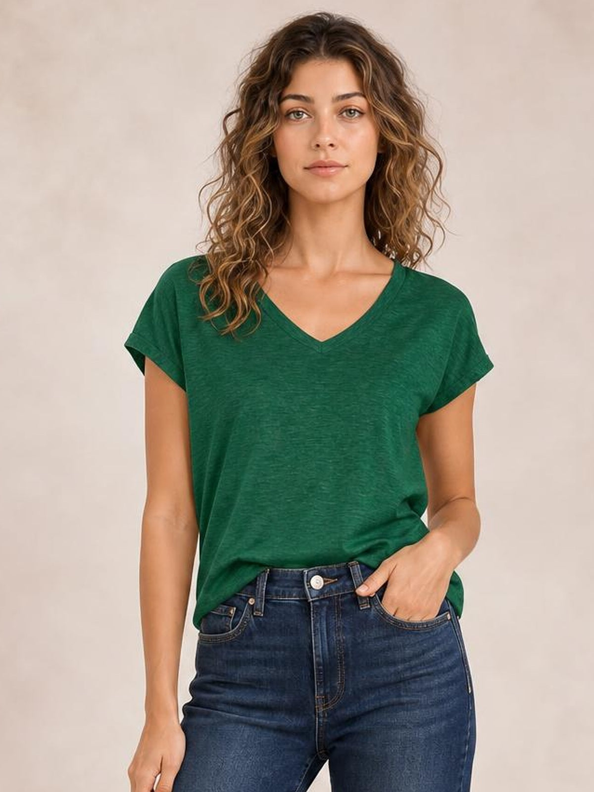 Model wearing a forest green V-neck short sleeve T-shirt with a relaxed silhouette, subtle heathered texture, and a straight hem partly tucked into jeans.