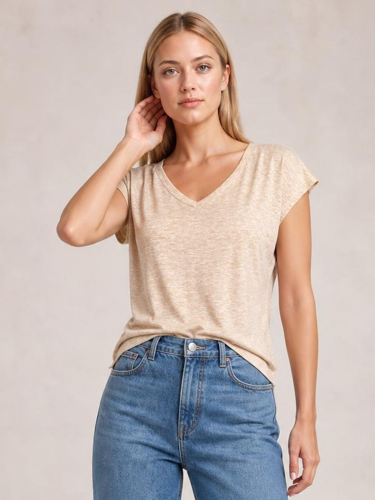 Model poses in a beige V-neck short sleeve T-shirt with a relaxed, straight silhouette and clean neckline construction.