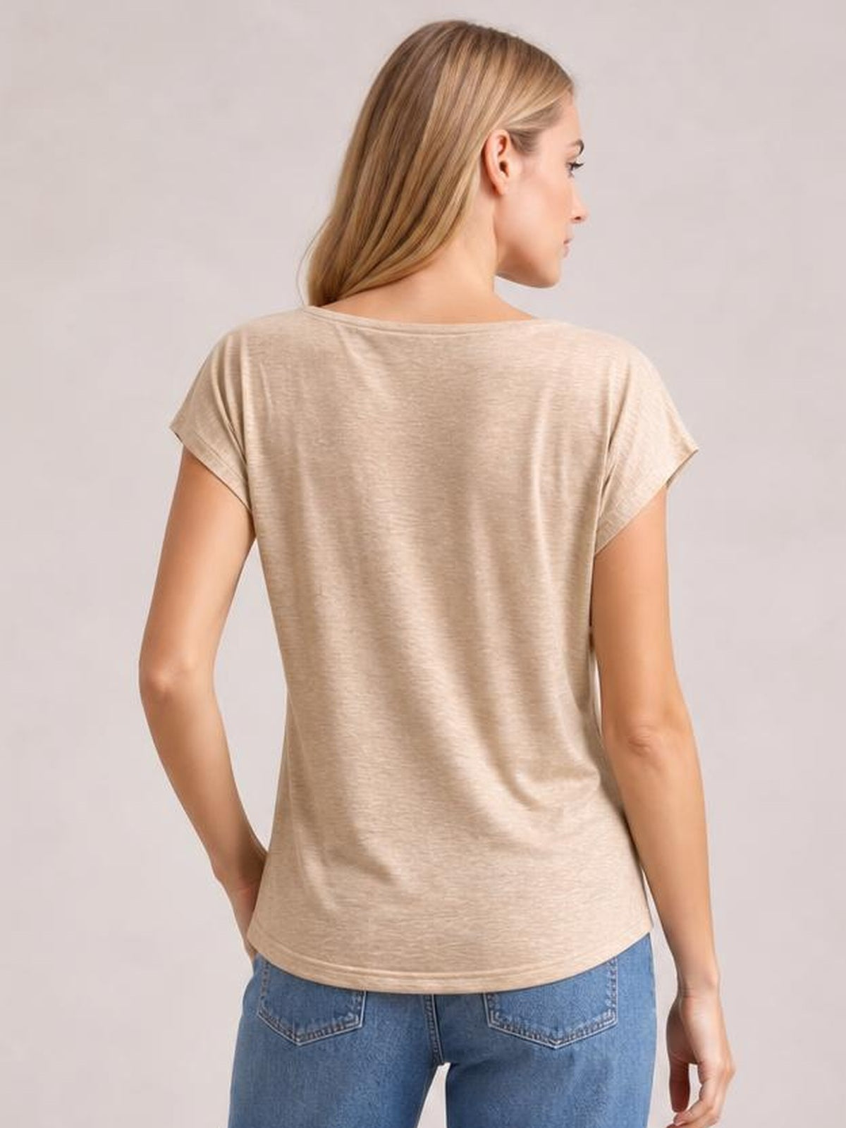 Model shown from the back in a beige short-sleeve T-shirt with a relaxed straight silhouette, simple construction, and a clean hem worn with jeans.