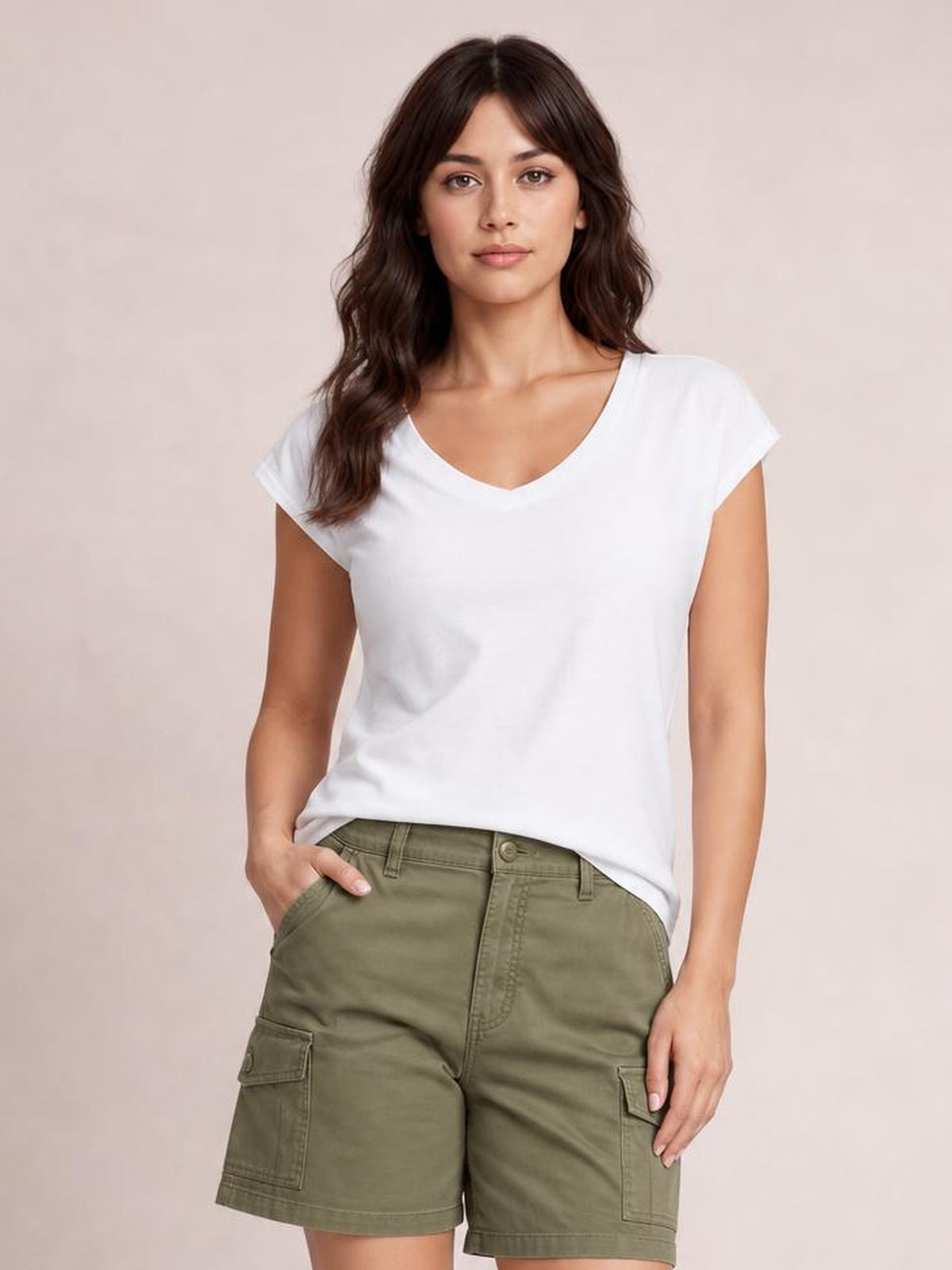 A model stands facing forward in a white V-neck short sleeve T-shirt with a basic straight silhouette, paired with olive cargo shorts and one hand in a pocket.