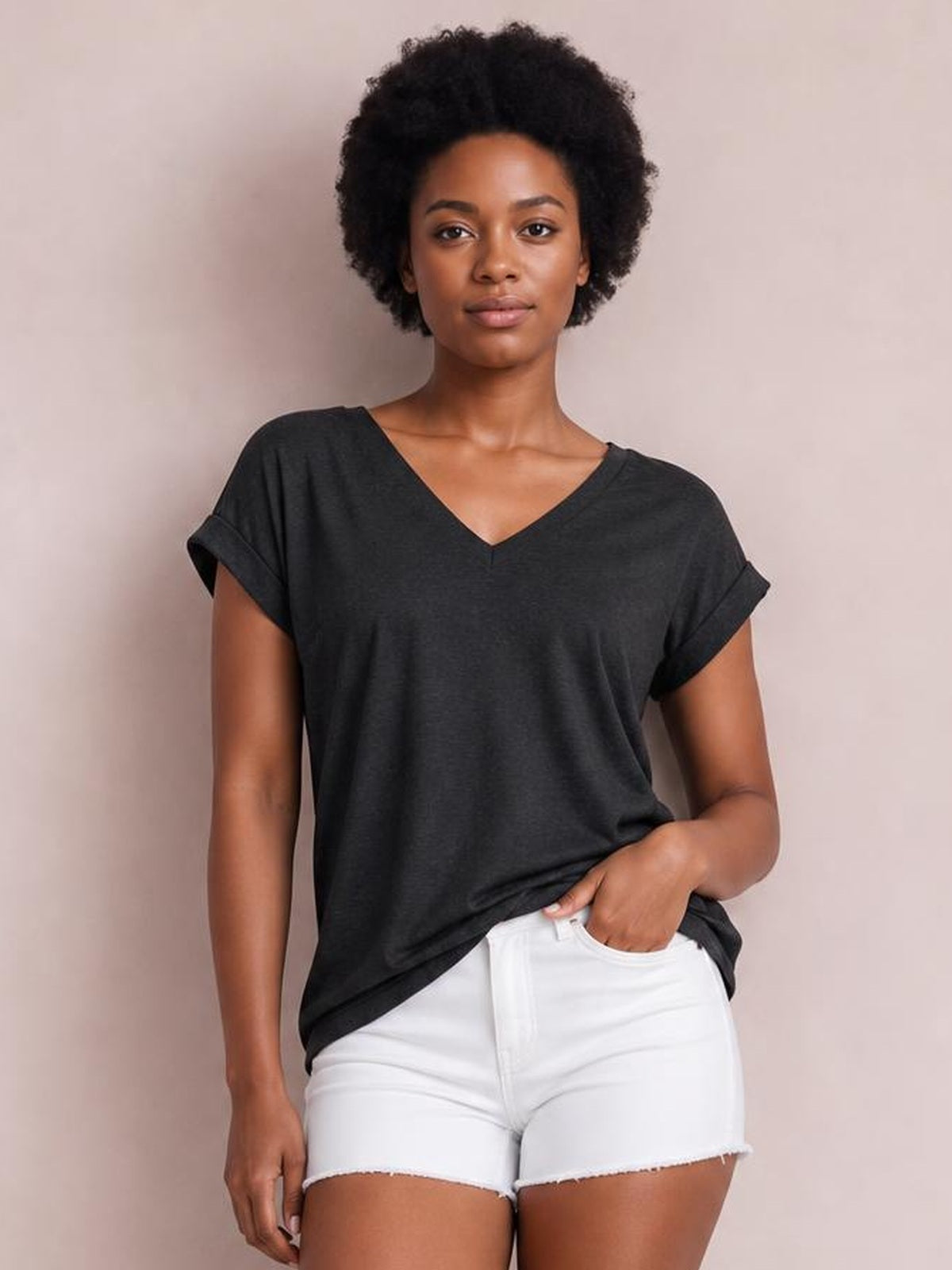 Model wearing a charcoal V-neck short sleeve T-shirt with rolled cuffs and a relaxed, slightly loose silhouette, paired with white shorts.