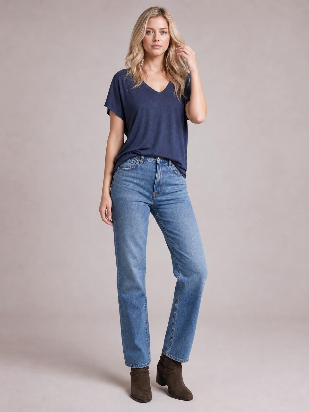 Model poses in a navy V-neck short sleeve T-shirt with a relaxed straight silhouette, draped hem, and slightly stretchy opaque fabric.